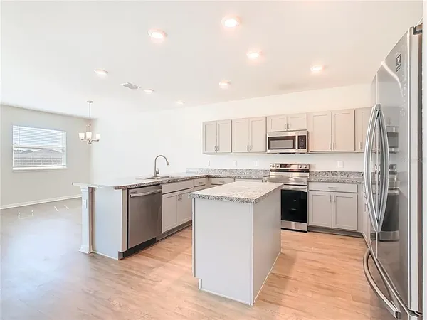 a kitchen with stainless steel appliances a refrigerator and wooden floor