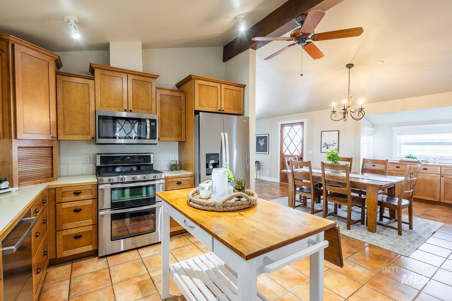 988 West King Road Kuna, ID 83634 - Photo 16 of 50 Kitchen with brown cabinets, light countertops, appliances with stainless steel finishes, healthy amount of natural light, and beamed ceiling