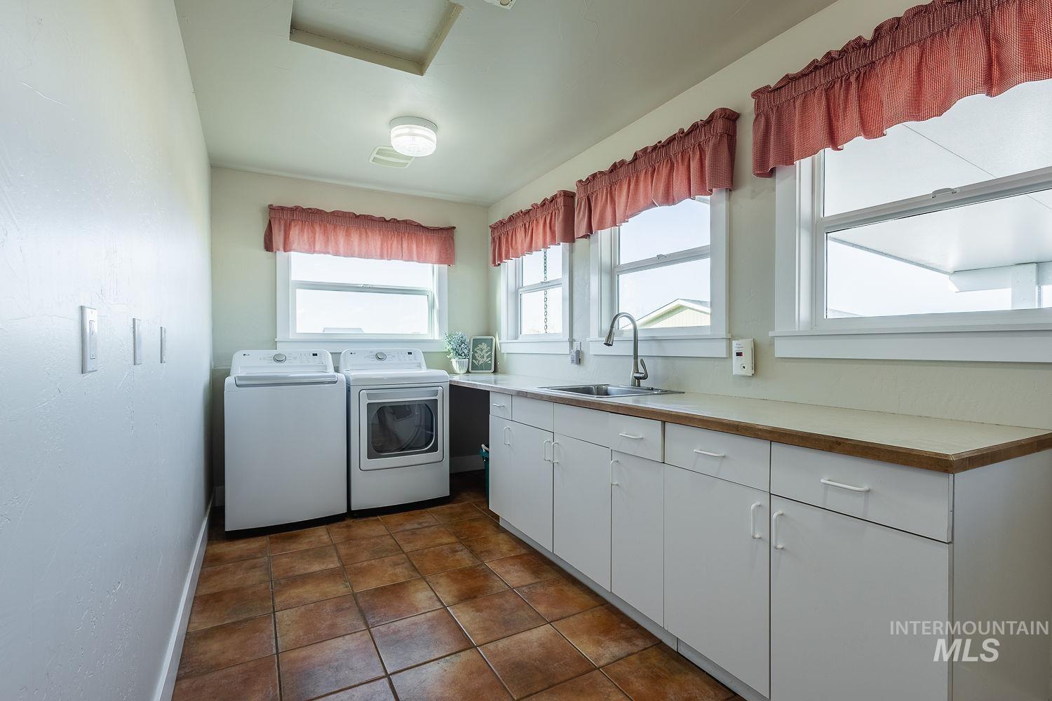 988 West King Road Kuna, ID 83634 - Photo 27 of 50 Laundry area with washing machine and clothes dryer, dark tile patterned floors, and cabinet space