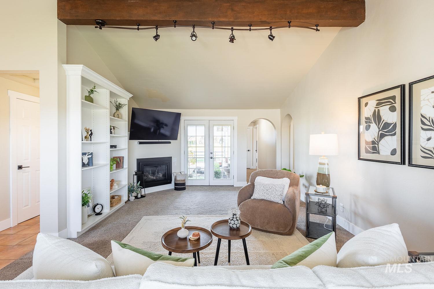 988 West King Road Kuna, ID 83634 - Photo 7 of 50 Living area featuring french doors, carpet floors, arched walkways, a glass covered fireplace, and high vaulted ceiling