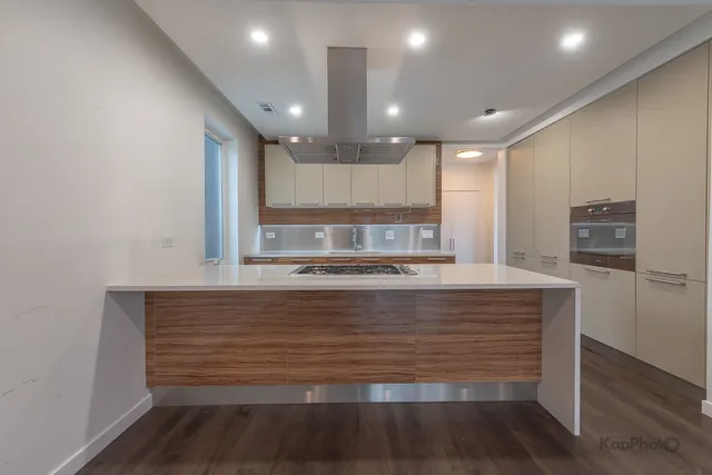 a view with kitchen island a sink wooden floor and stainless steel appliances