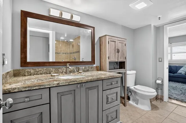a bathroom with a granite countertop toilet a sink and a mirror