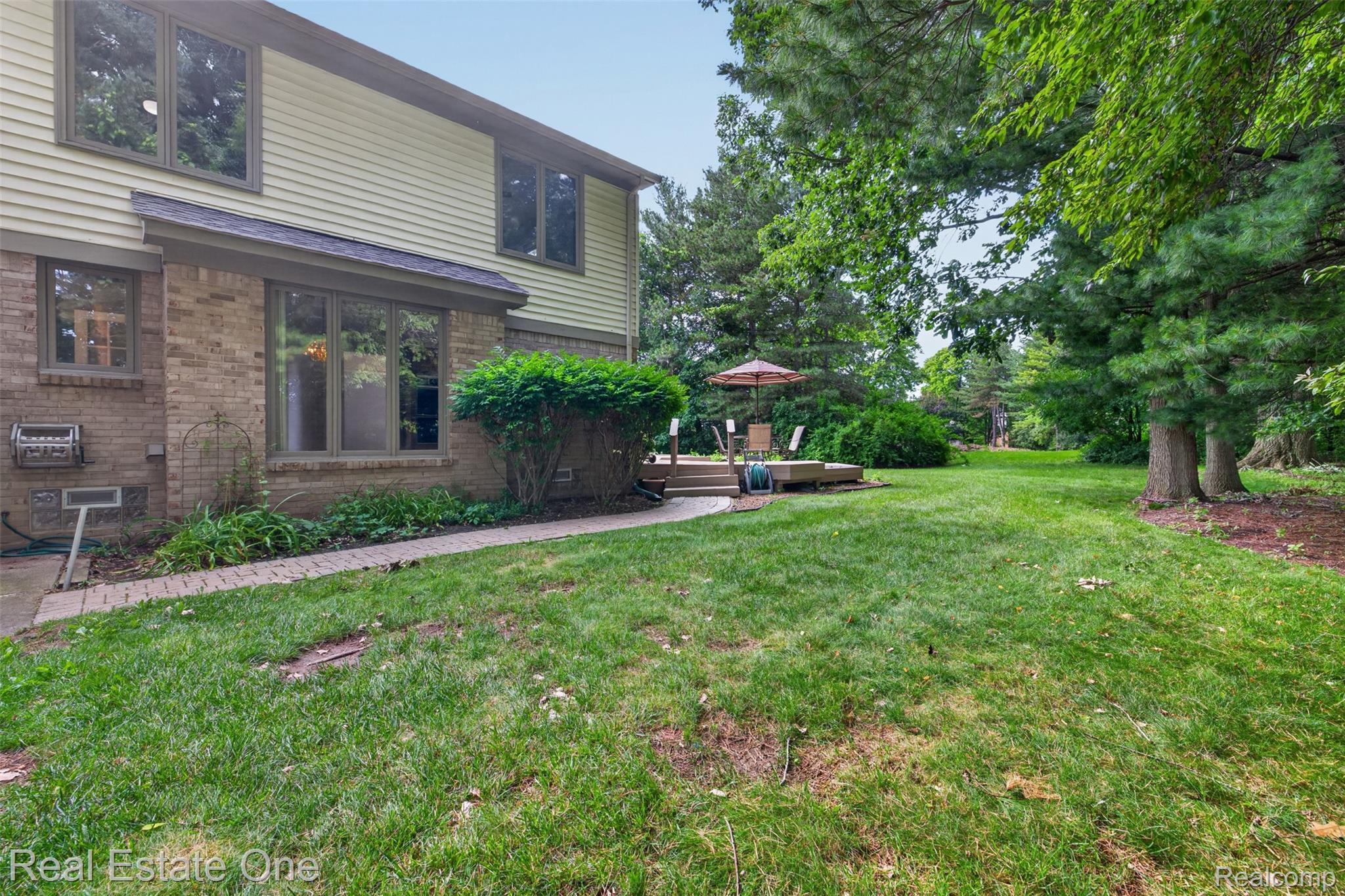 3400 Wedgewood Drive Rochester, MI 48306 - Photo 40 of 49 Expansive backyard featuring a lush lawn, mature trees, and a ground-level wood-finish deck
