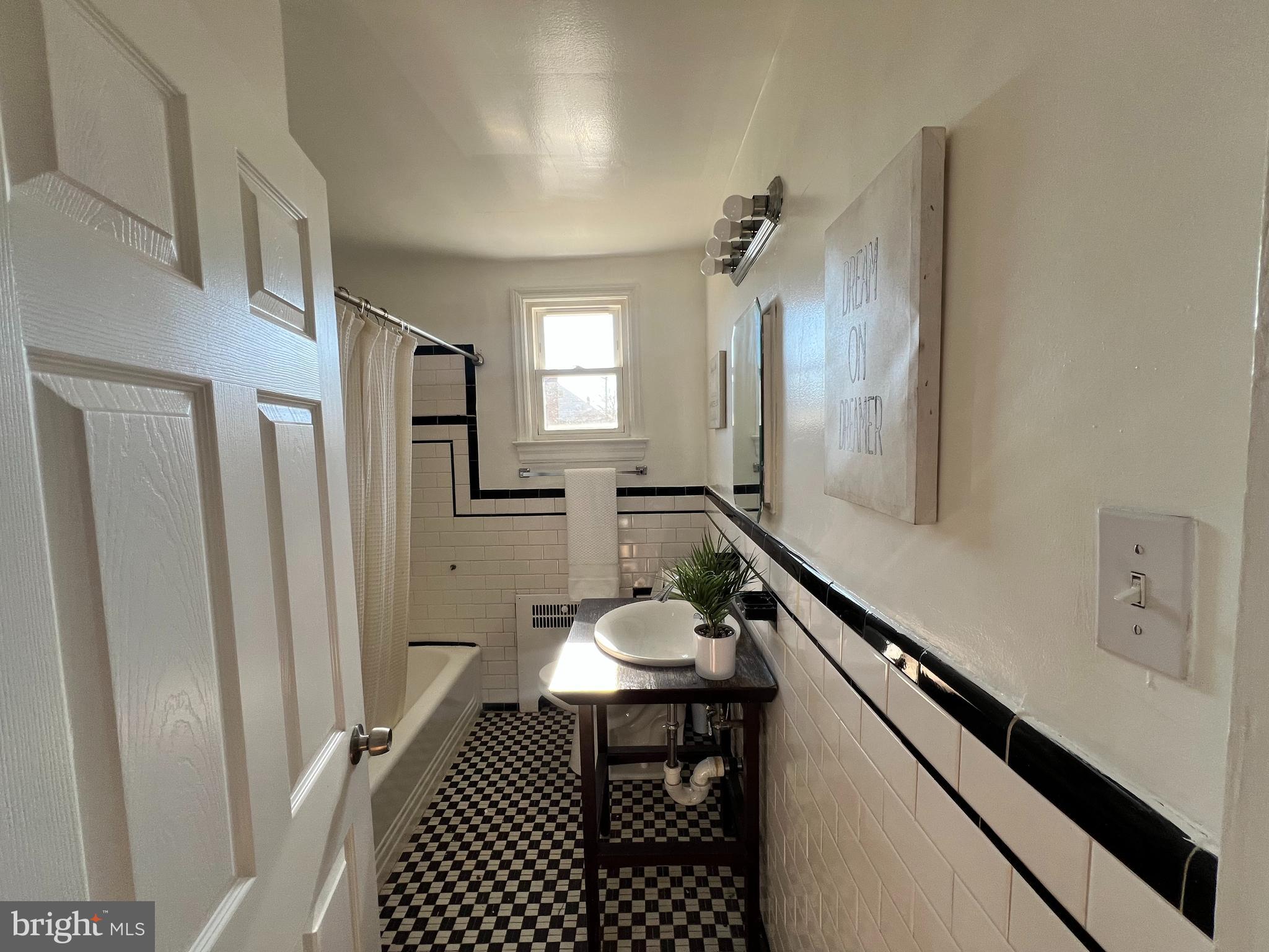 56 Yorkway Baltimore, MD 21222 - Photo 8 of 23 a bathroom with a sink a mirror a vanity and a shower