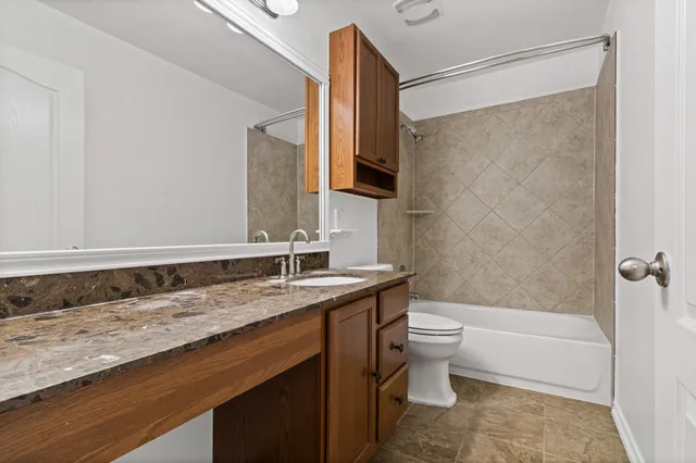 a bathroom with a granite countertop sink a toilet and shower