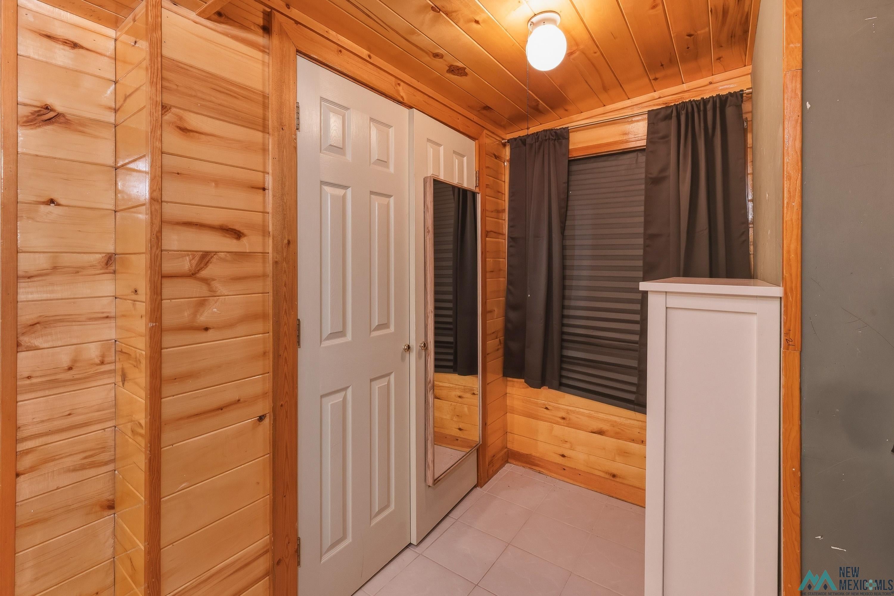 1432 South 5th Street Raton, NM 87740 - Photo 14 of 32 Hallway with wood walls, wood ceiling, and light tile patterned floors