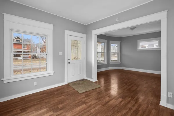 a view of an empty room with wooden floor and a window