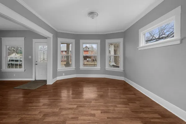 a view of empty room with wooden floor and window