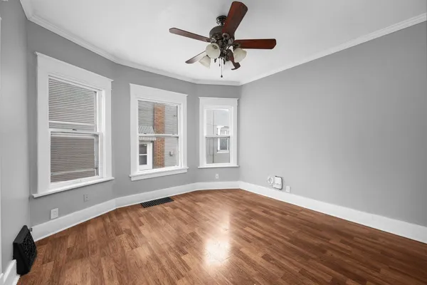 a view of an empty room with a window and wooden floor