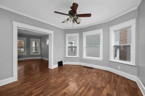 a view of an empty room with a window and wooden floor