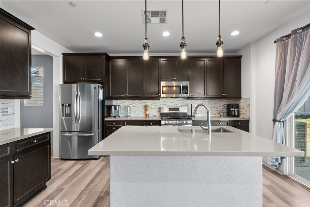 6949 Beale Road Palmdale, CA 93552 - Photo 8 of 32 a kitchen with stainless steel appliances granite countertop a refrigerator a sink a stove a microwave and wooden cabinets