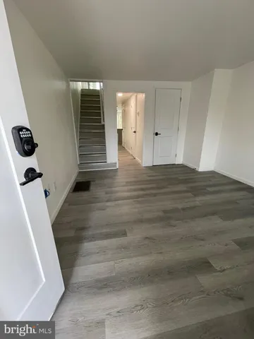 a view of an empty room with wooden floor and windows