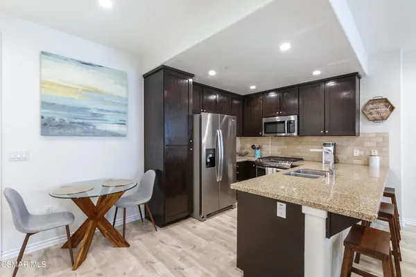 a kitchen with stainless steel appliances granite countertop a refrigerator a stove a sink a dining table and chairs