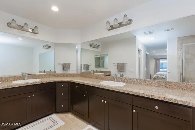 a spacious bathroom with a granite countertop sink double and mirror