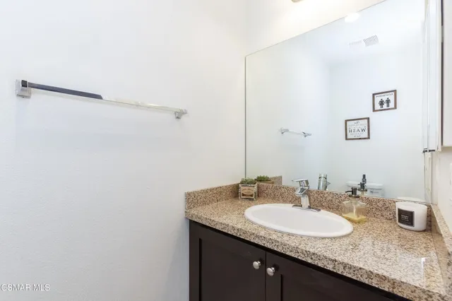 a bathroom with a granite countertop sink and a mirror