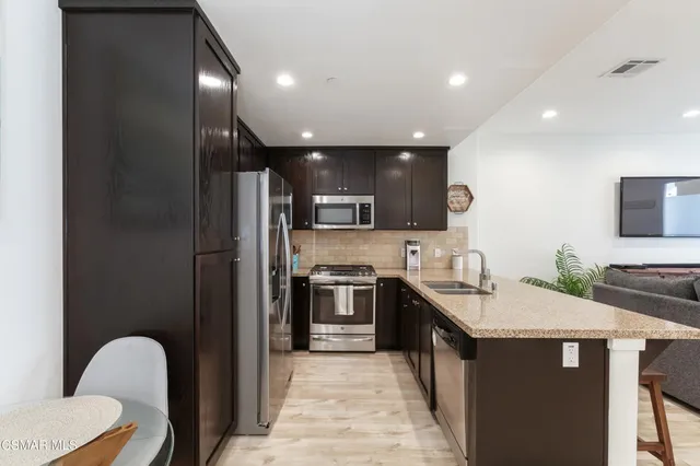 a kitchen with stainless steel appliances granite countertop a sink a stove a refrigerator and a oven