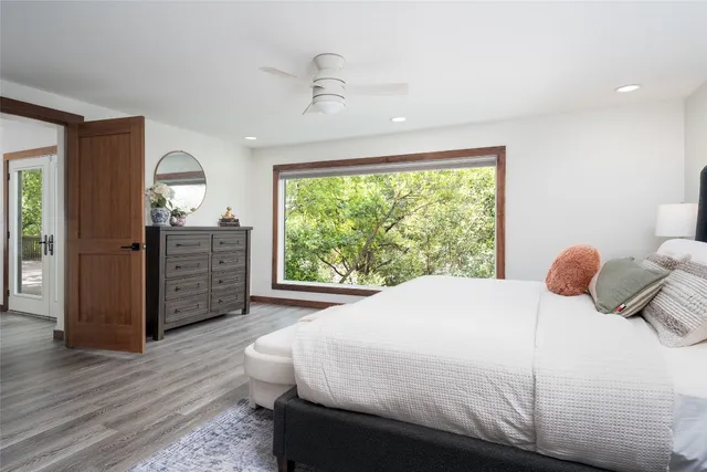 a bedroom with a bed dresser and a large window