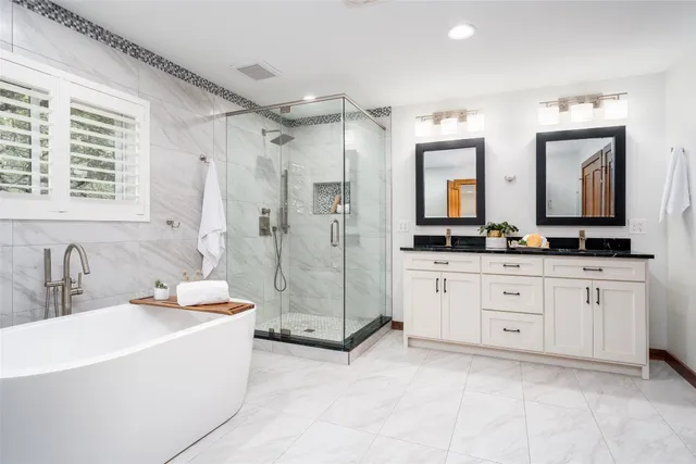 a bathroom with a double vanity sink mirror and a bathtub