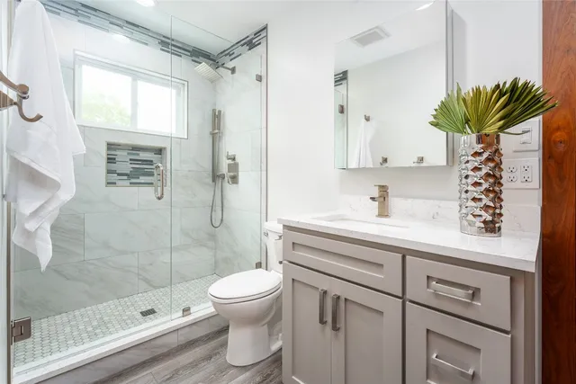 a bathroom with a shower sink vanity mirror and toilet
