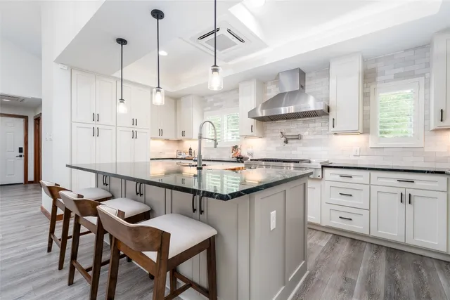 a kitchen with stainless steel appliances granite countertop a sink a stove and a wooden floors