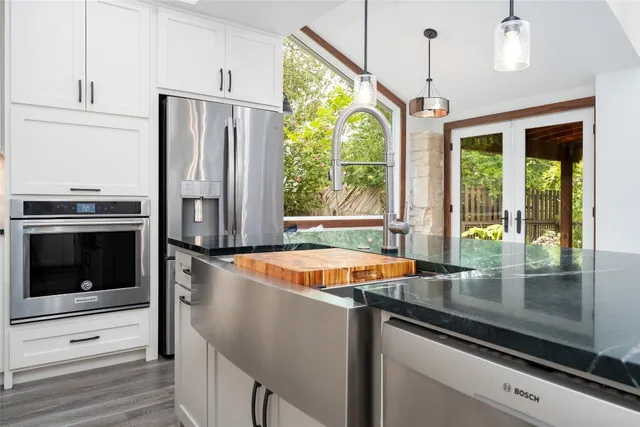 a kitchen with stainless steel appliances granite countertop a refrigerator a sink and a stove