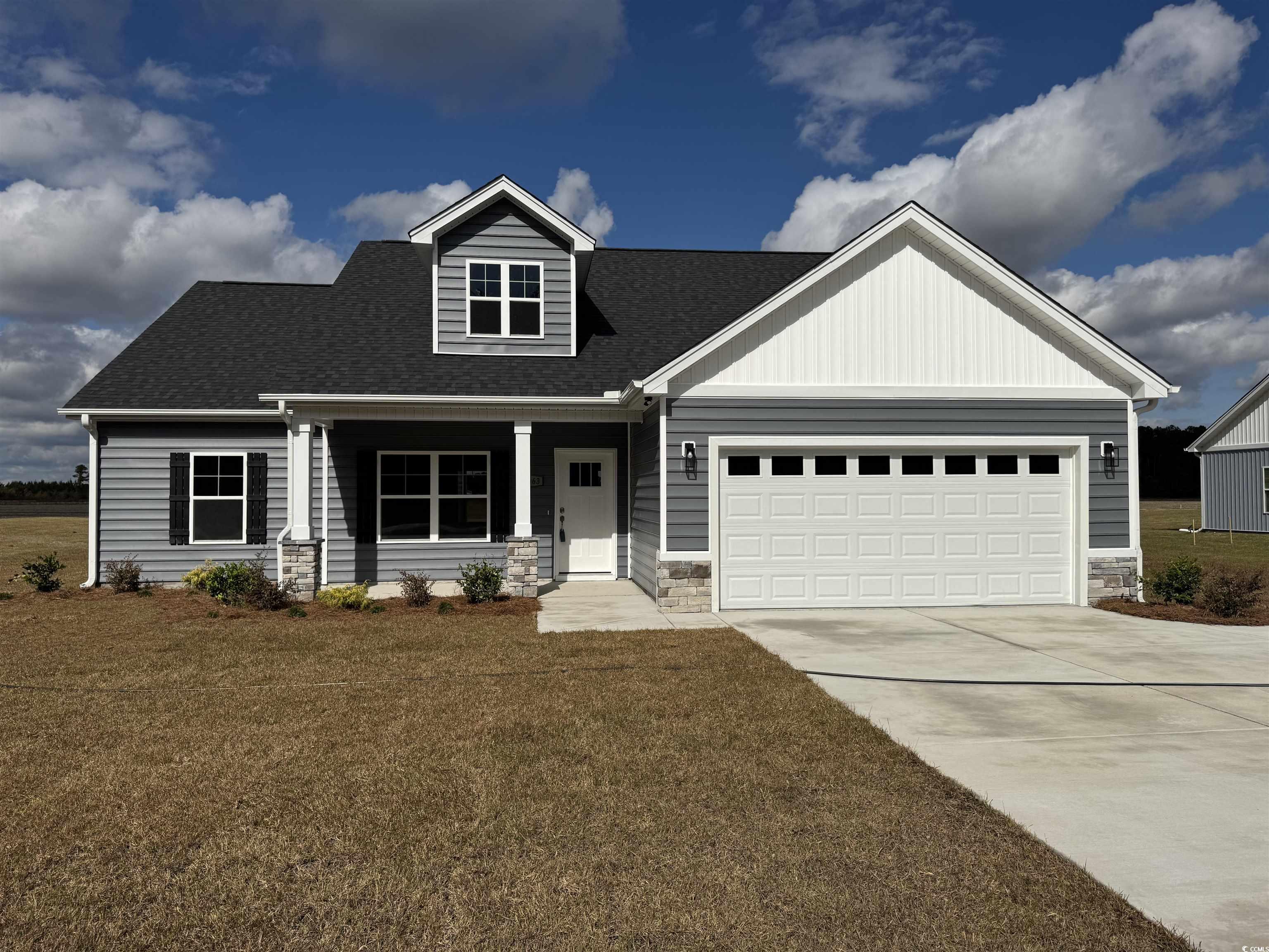 View of front facade with stone siding, covered porch, a shingled roof, and driveway