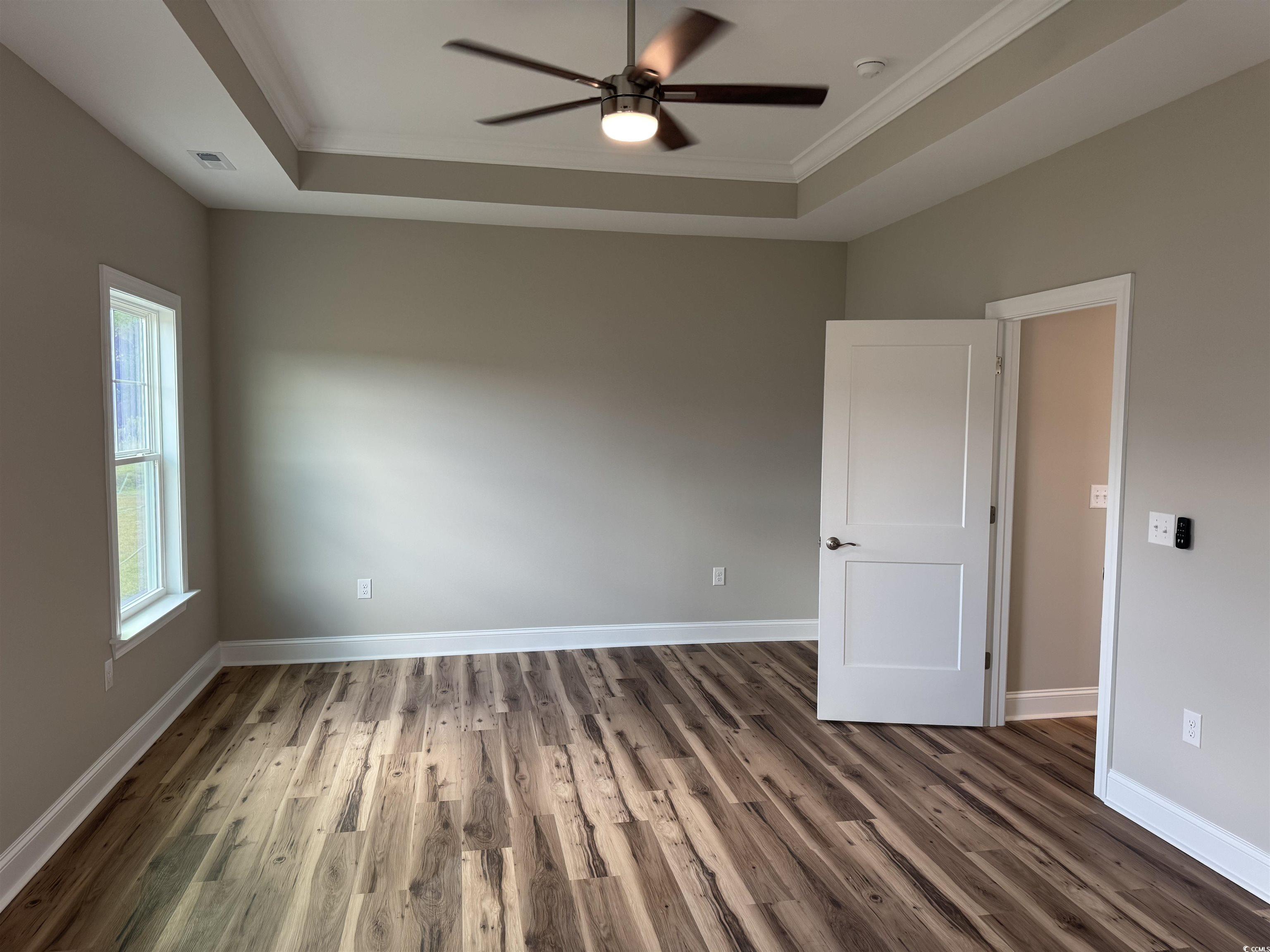 4963 Dupont Road Aynor, SC 29511 - Photo 8 of 18 Spare room with a raised ceiling, ornamental molding, wood finished floors, and a ceiling fan