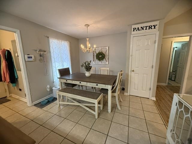 395 Austin Street Savannah, TN 38372 - Photo 7 of 32 Dining area featuring neutral wall paint, a multi-light chandelier, a white six-panel door, and square tile flooring
