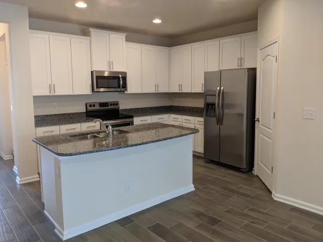 a kitchen with kitchen island granite countertop a sink a stove and cabinets