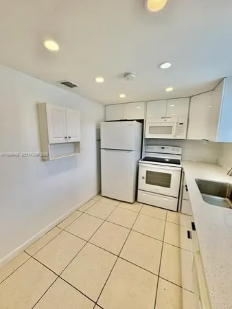 a kitchen with a refrigerator a stove top oven and white cabinets