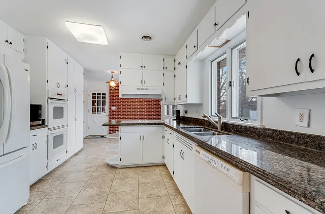 a large white kitchen with granite countertop a sink