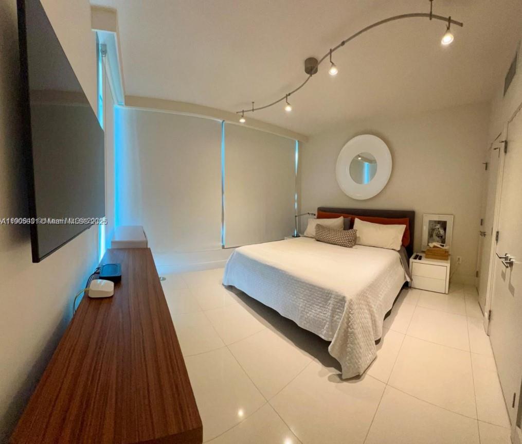 6899 Collins Avenue, Unit 1709 Miami Beach, FL 33141 - Photo 15 of 18 a bedroom with a bed and a chandelier