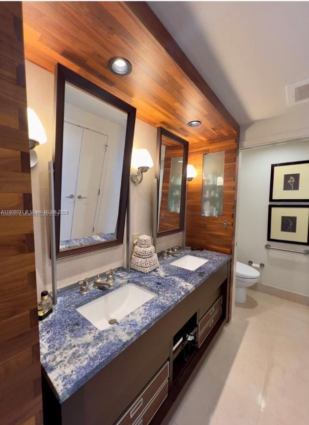 6899 Collins Avenue, Unit 1709 Miami Beach, FL 33141 - Photo 16 of 18 a bathroom with a granite countertop sink a toilet and a mirror