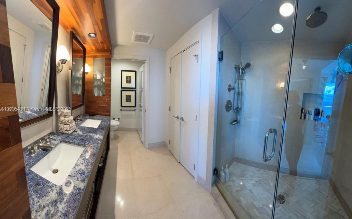6899 Collins Avenue, Unit 1709 Miami Beach, FL 33141 - Photo 17 of 18 a bathroom with a double vanity sink toilet and shower