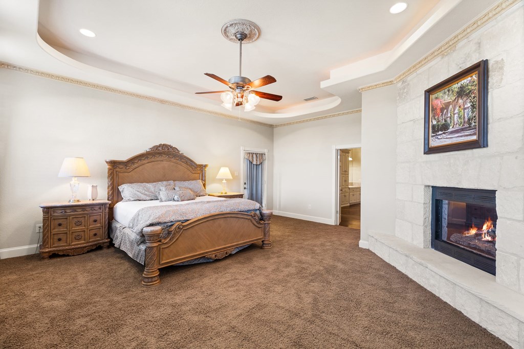 157 McCullough Ranch Road Kerrville, TX 78028 - Photo 41 of 75 a bedroom with a bed and a fireplace