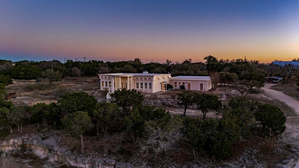 157 McCullough Ranch Road Kerrville, TX 78028 - Photo 70 of 75 a view of a house in a field with lots of plants and trees