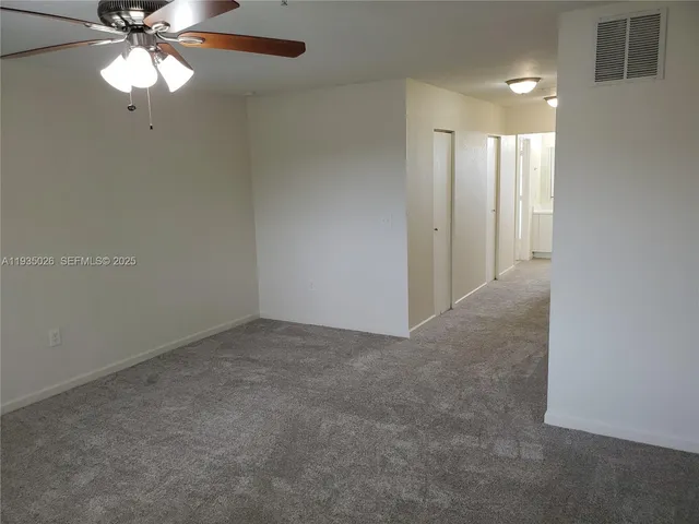 an empty room with a fan & a chandelier fan