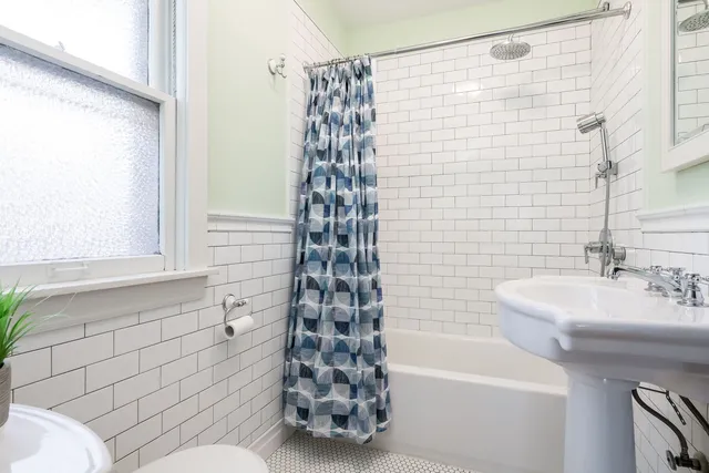 a bathroom with a sink a toilet a window and shower