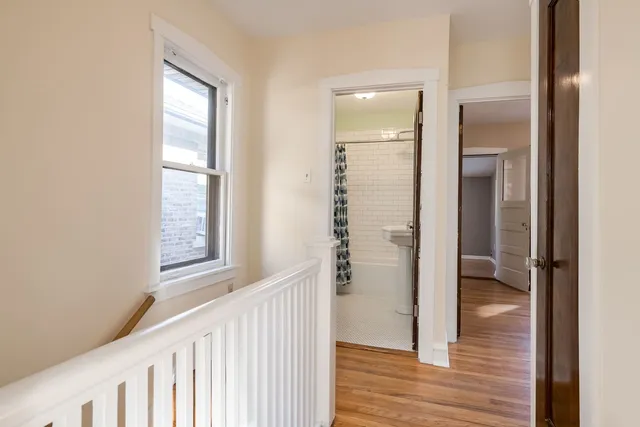 a view of a hallway with wooden floor and a bathroom