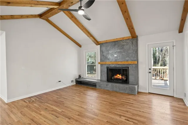 a view of an empty room with wooden floor fireplace and a window