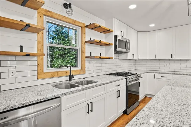 a kitchen with granite countertop a sink stainless steel appliances and cabinets
