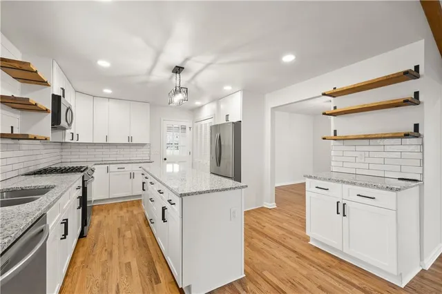 a large kitchen with stainless steel appliances granite countertop a lot of counter space and wooden floors