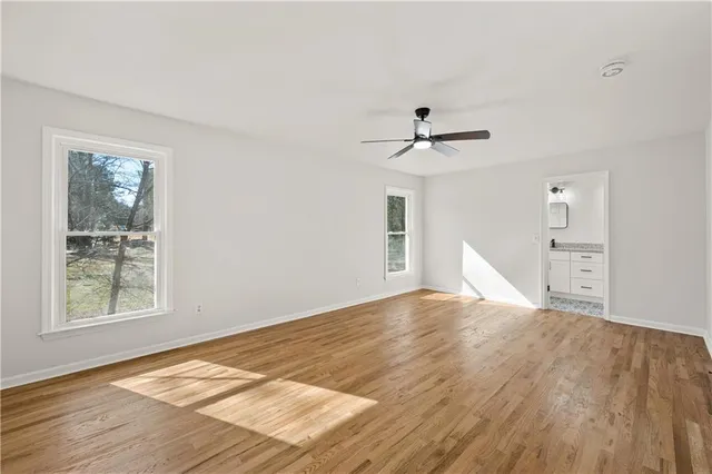 a view of empty room with wooden floor and fan