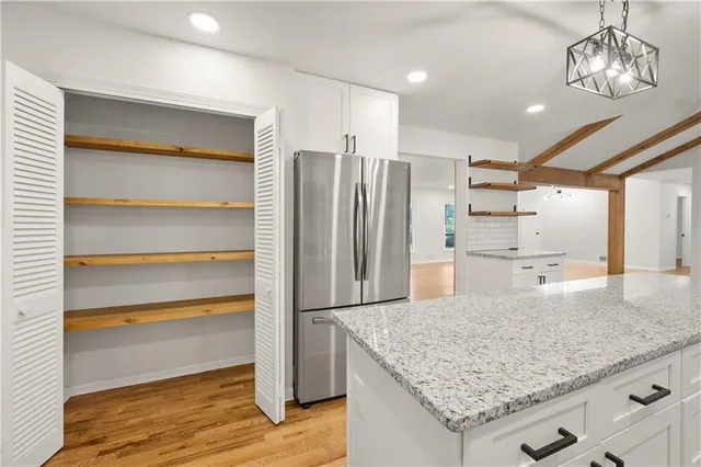 a kitchen with kitchen island granite countertop a refrigerator and a sink