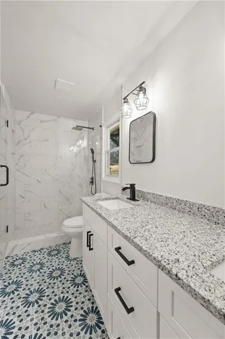 a bathroom with a granite countertop sink a toilet and mirror