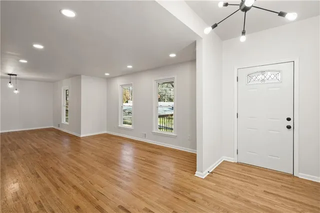 a view of an empty room with wooden floor and a ceiling fan