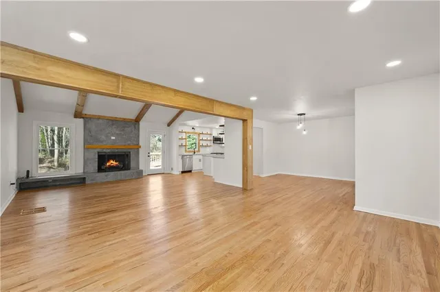 an empty room with wooden floor fireplace and windows
