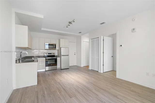 a kitchen with stainless steel appliances granite countertop a sink and wooden floors
