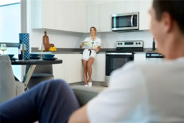 a living room with furniture a flat screen tv and kitchen view