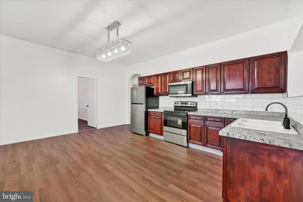 a kitchen with stainless steel appliances granite countertop a sink dishwasher stove and refrigerator with wooden floor
